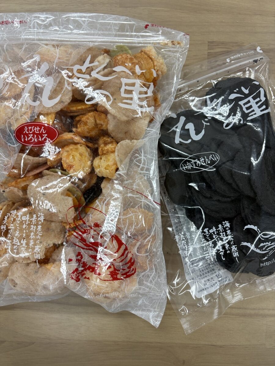 Ebi Senbei no Sato assorted shrimp crackers — a mixed 'Ebisen Iroiro' bag and a squid-ink variety in resealable packs — purchased and photographed by the Kasegeya editorial team (えびせんべいの里・編集部が実際に購入して撮影)