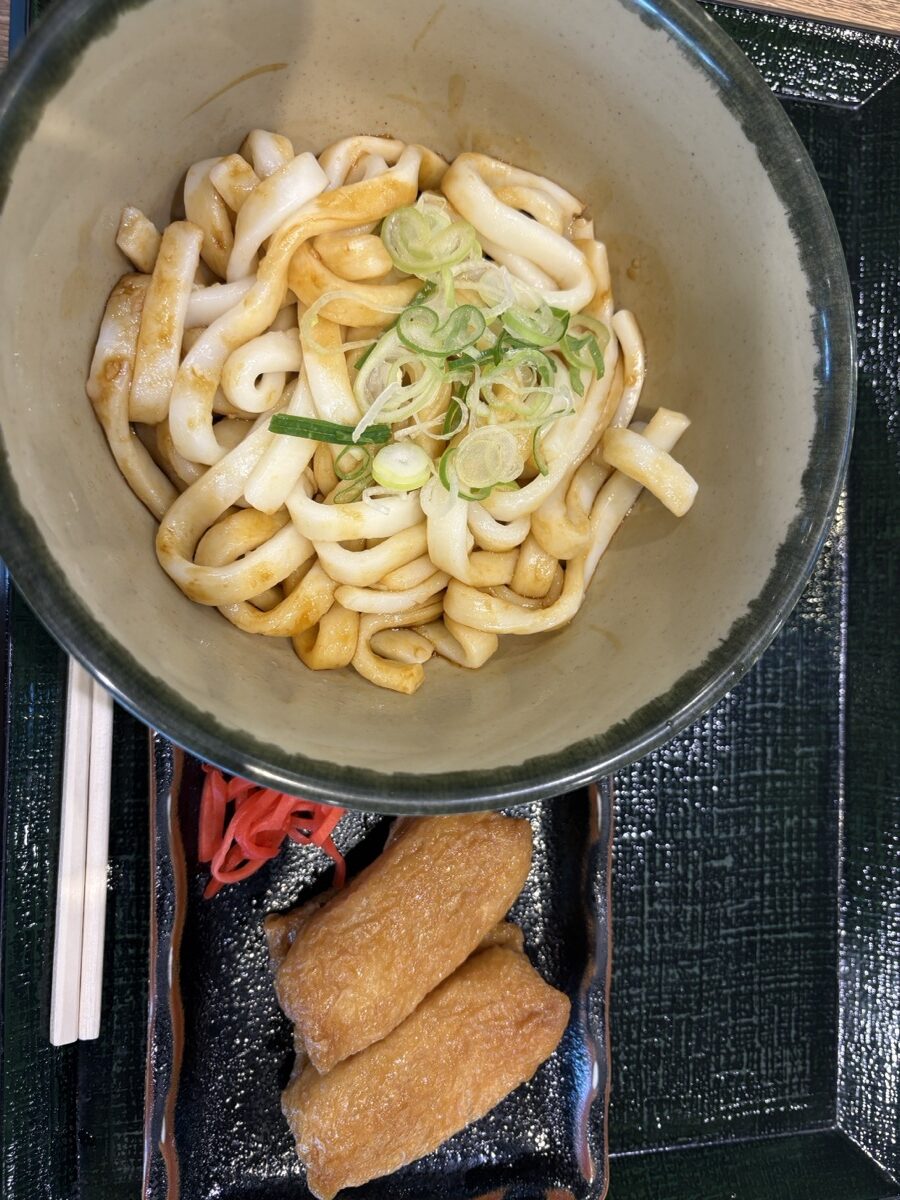 Ise udon — thick, soft noodles in dark tamari-based tare with green onion, served with inari-zushi — eaten and photographed by the Kasegeya editorial team in Mie (伊勢うどん・編集部が実際に食べて撮影)